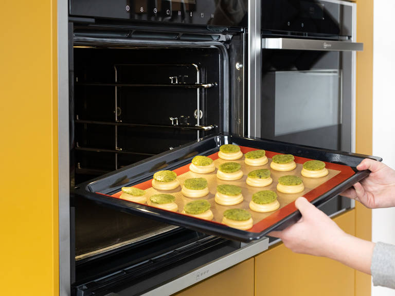 Remove pistachio crumble sheet from the freezer and use a round cookie cutter to press out circles. Place one onto each of the cream puffs and transfer to the preheated oven. Bake at 180°C/355°F for approx. 30 - 35 min., until golden brown.